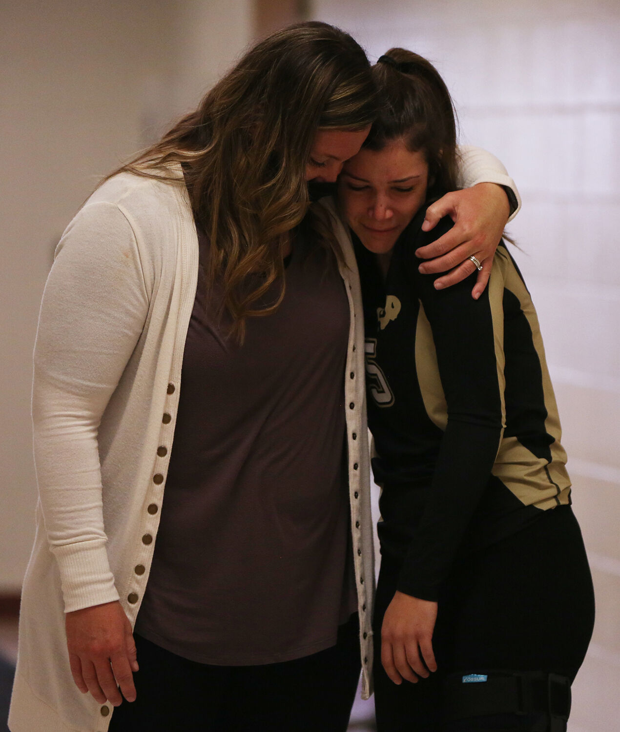 Riley Fowler hugs assistant coach Sarah Walker in the hallway